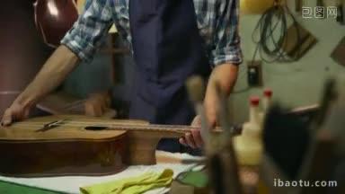 琵琶制作店和古典乐器年轻的成年工匠修理老古典吉他的男人仔细看着桥